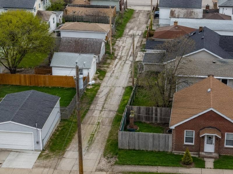 Aerial view of a former municipal alley running between fenced residential lots and backyard garages.